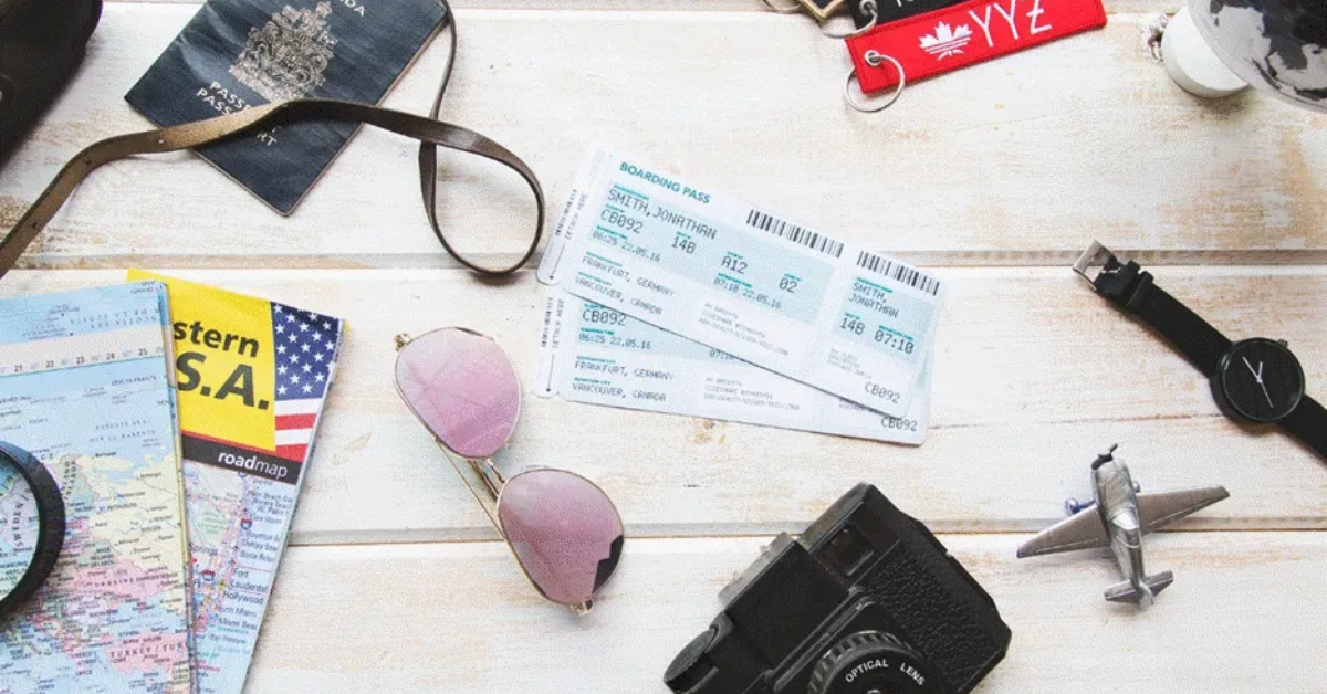 A boarding pass on a table beside a camera, sunglasses, and a passport