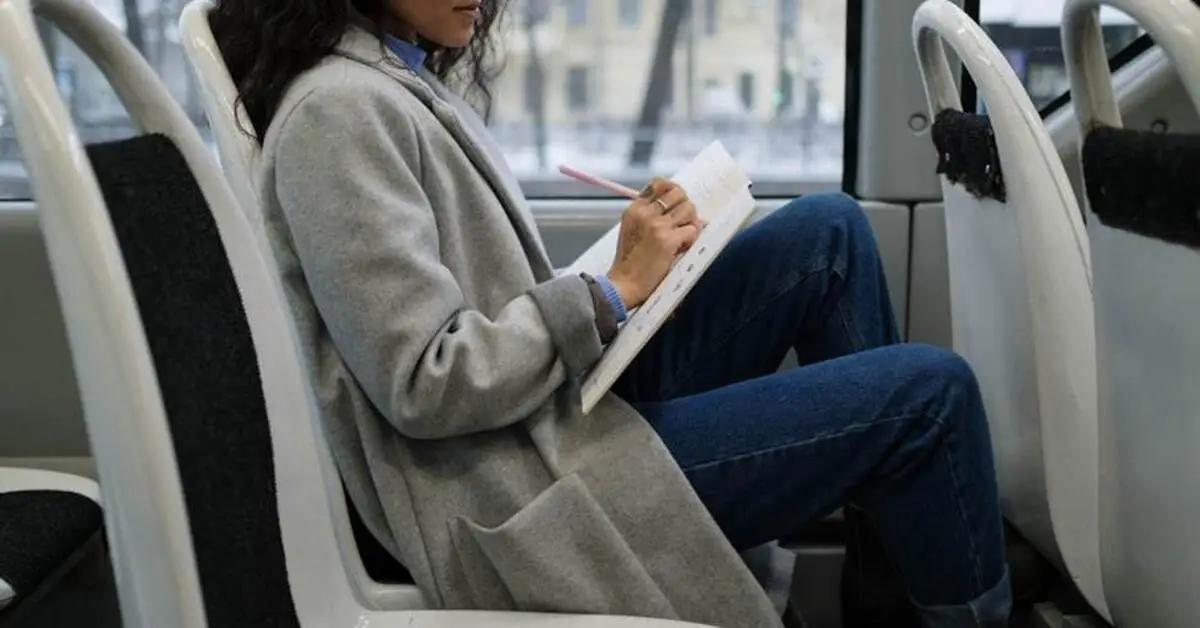A woman writing in her notebook inside a bus