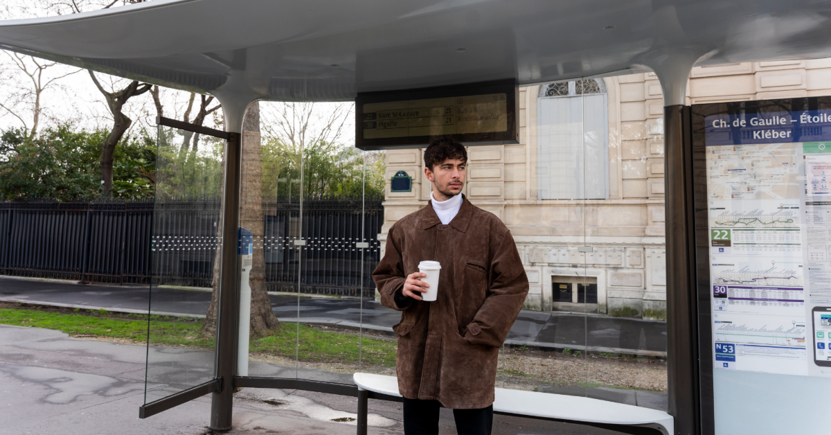 A man waiting for the F15 bus under a shaded bus stop