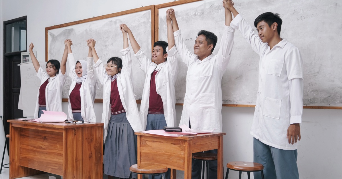 Students Wearing Lab Coats Raise Hands Up to Celebrate Their Achievements
