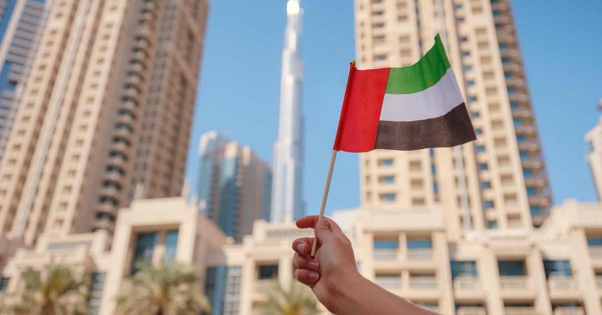 Dubai landscape with a hand holding the UAE flag