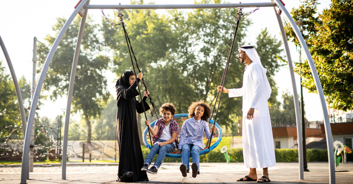 family playing on swings in a park