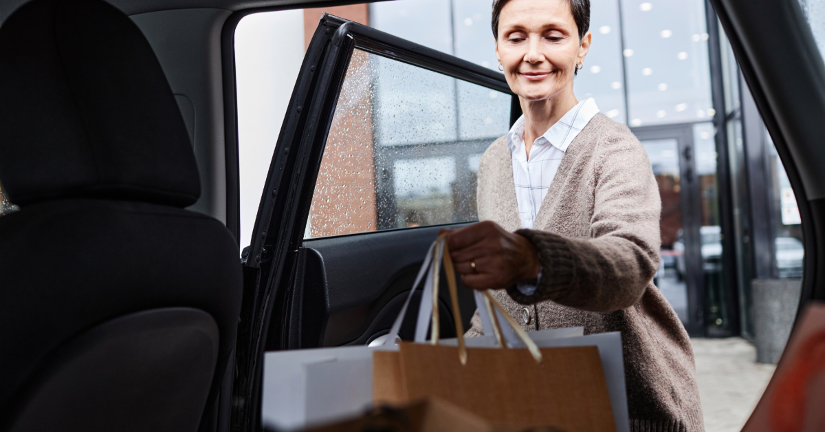 Woman loading paper bags in a taxi outside a shopping mall