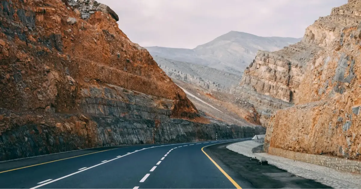 The roadway, surrounded by hills, creates a scenic route