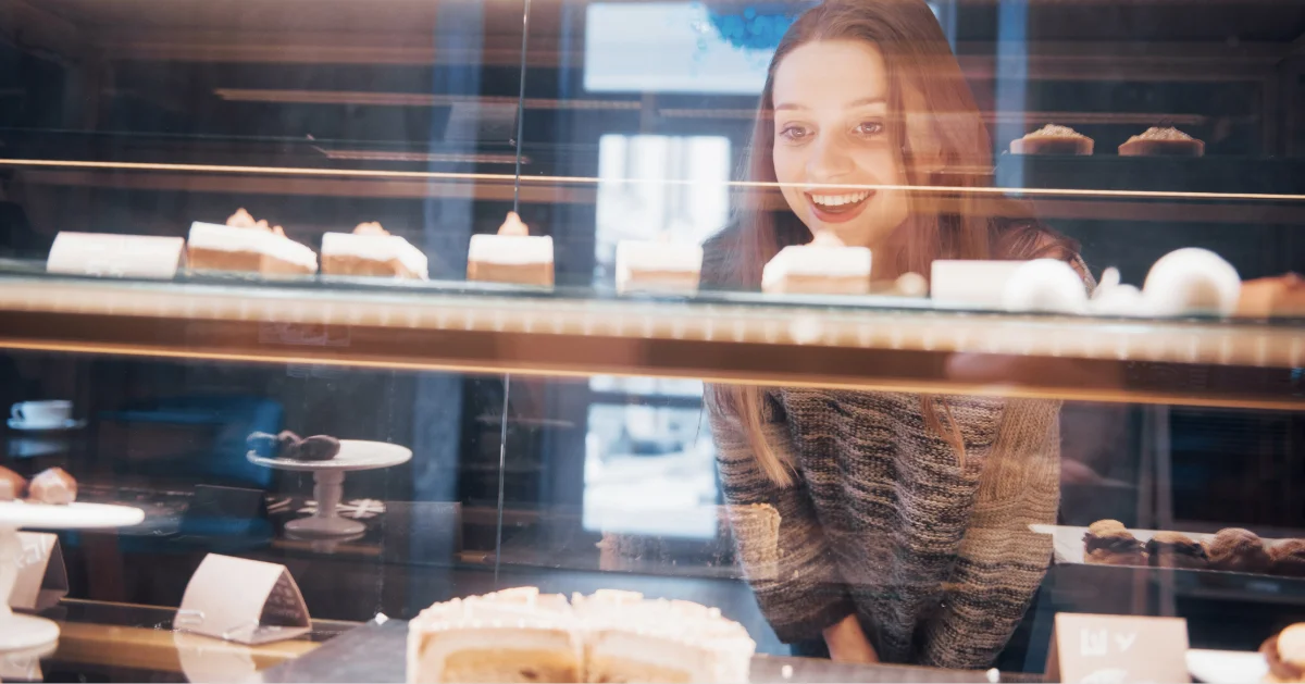 a woman choosing a cake from a display