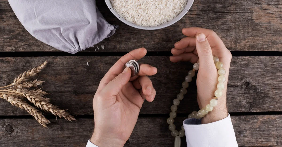 صورة يد تمسك نقود معدنية مقدمة زكاة الفطر في الإمارات