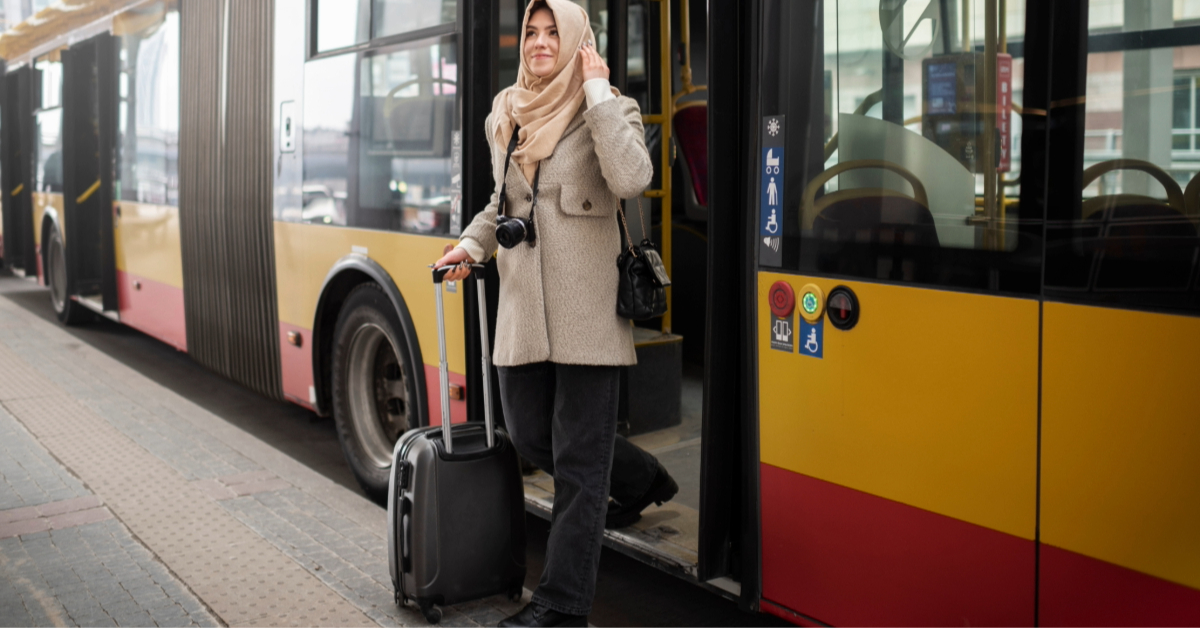 A woman getting down from an RTA bus with her luggage