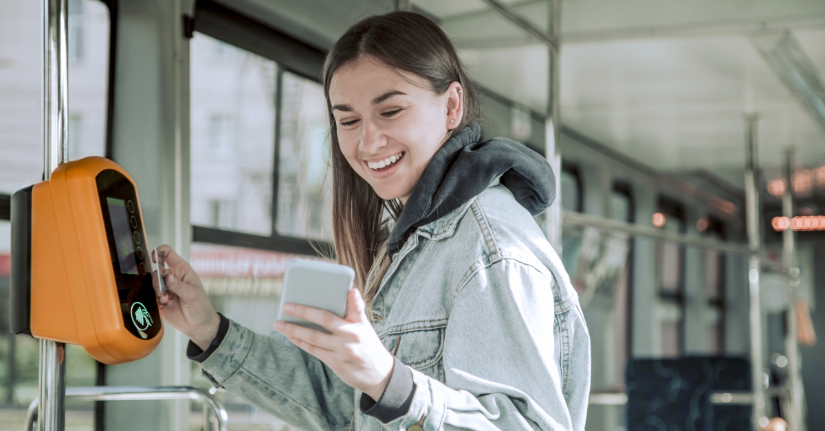A smiling woman tapping her card to board the bus