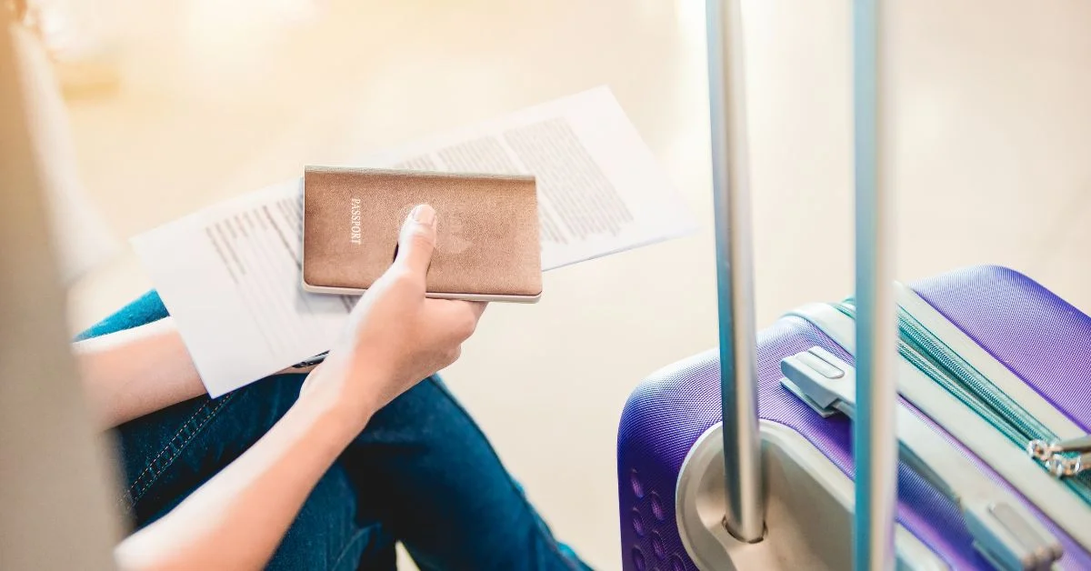 Traveller holding documents and passport, awaiting beside the luggage