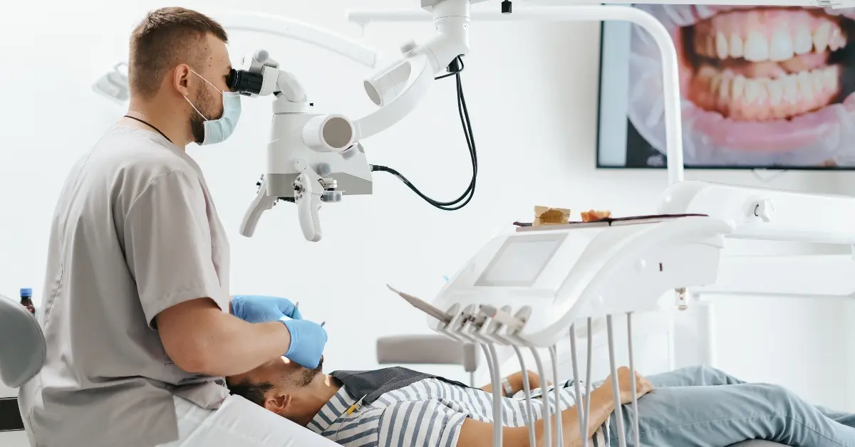 A dentist examining a patient’s teeth in a dental treatment room.