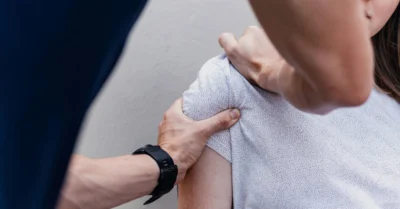 A woman having her shoulders checked by the doctor