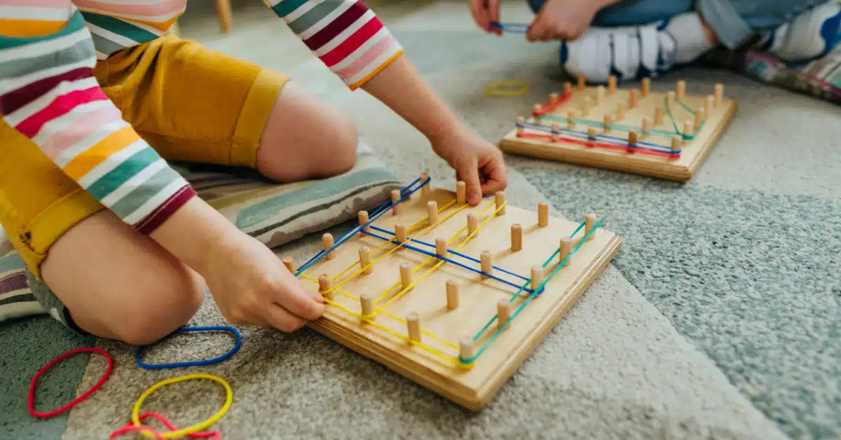 Preschool students playing with a geoboard, wrapping rubber bands