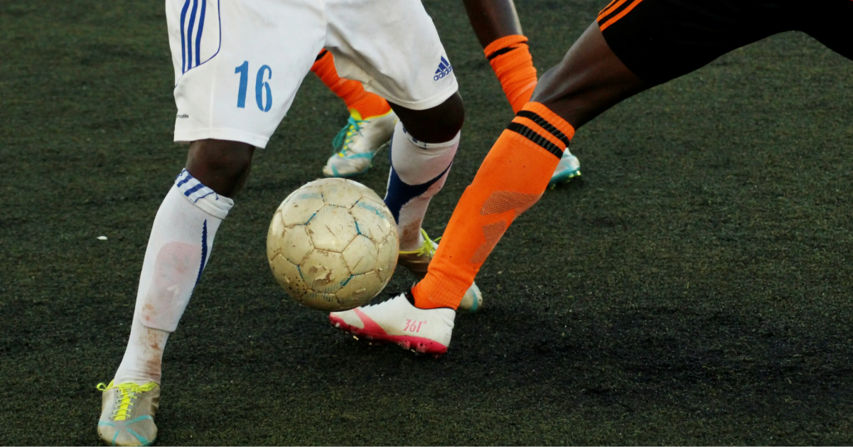 Two opposing football players competing for the final goal kick