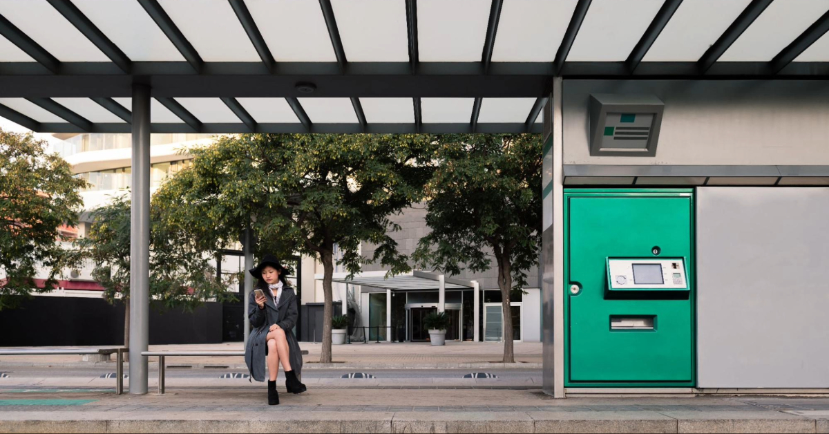 A woman consulting phone and waiting the bus