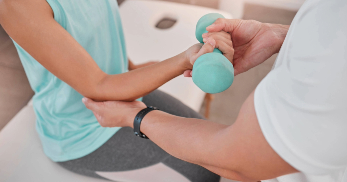 Physiotherapist helping a woman with dumbbells for rehabilitation