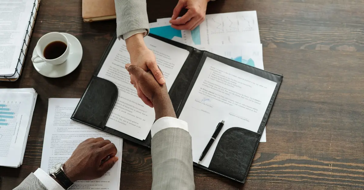 Individuals signing papers after an agreement