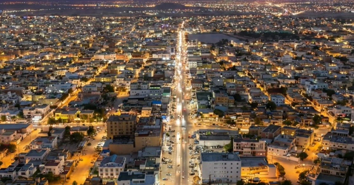 صورة بانورامية لمدينة خورفكان ليلًا تُظهر المنازل والطرق المضيئة في مشهد حضري هادئ وجذاب.