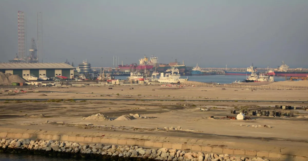 مشهد جوي لميناء جبل علي في دبي يظهر الرافعات العملاقة والحاويات المصطفة بجانب الأرصفة البحرية المترامية.