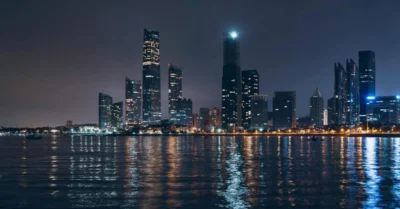 A wide view of Abu Dhabi at night with clear blue water