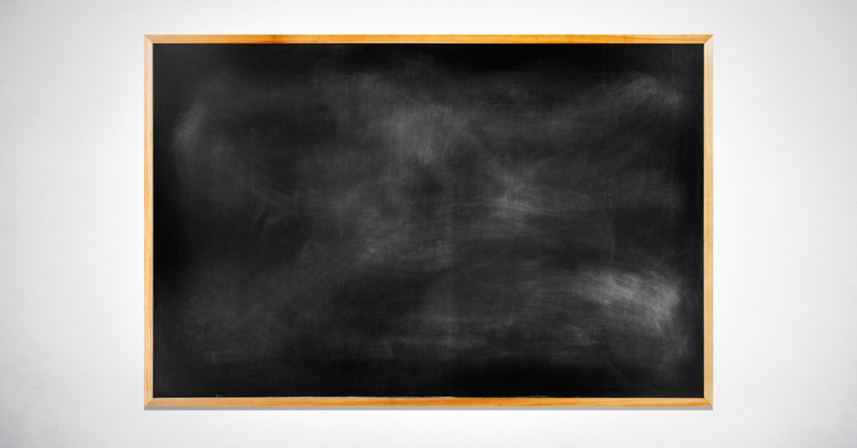 Blank black chalkboard on a white wall
