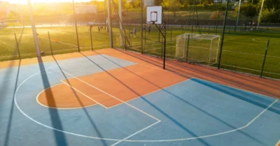 Outdoor basketball court at sunset with long shadows and warm light