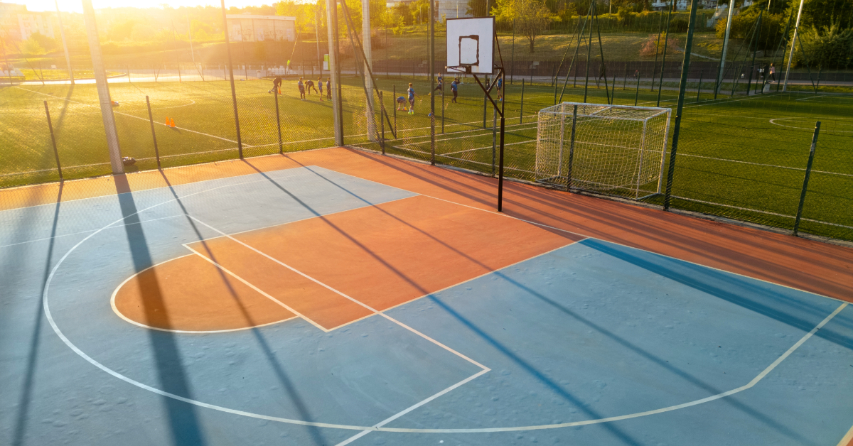 Outdoor basketball court at sunset with long shadows and warm light
