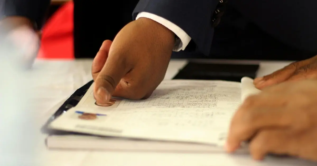 موظف في مركز سعادة المتعاملين بهيئة الهوية يقوم بتسليم بطاقة الهوية الجديدة لأحد المراجعين