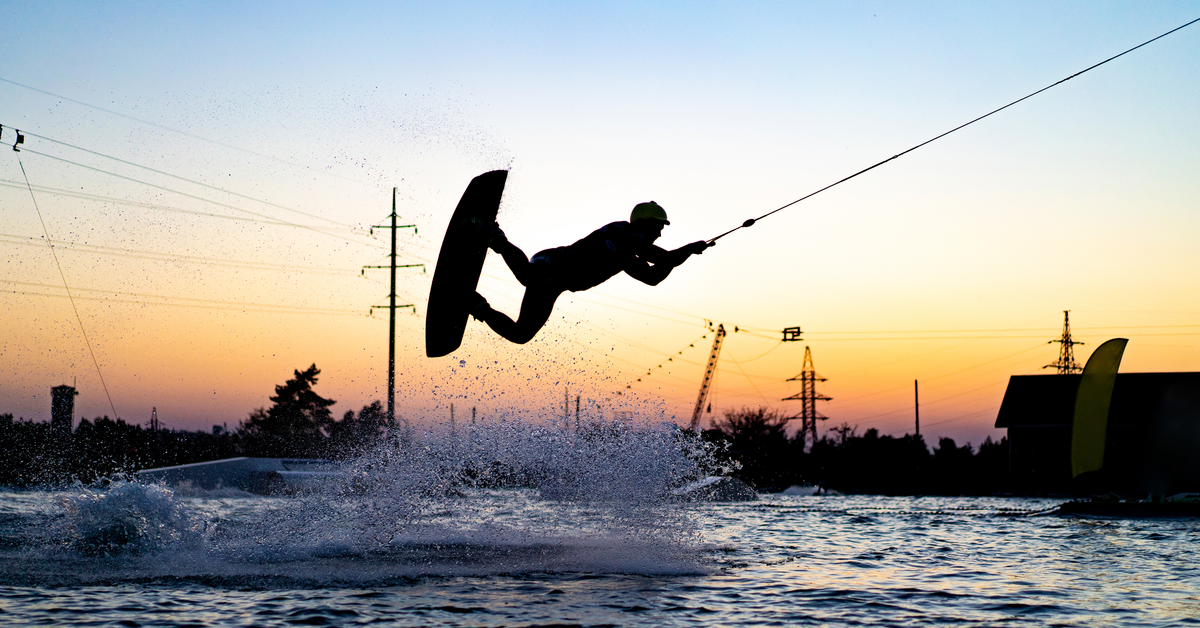 Wakeboarder performs an air trick over a ramp on a lake