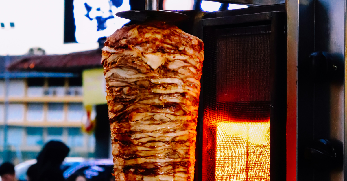 A chicken shawarma rod in front of the fire