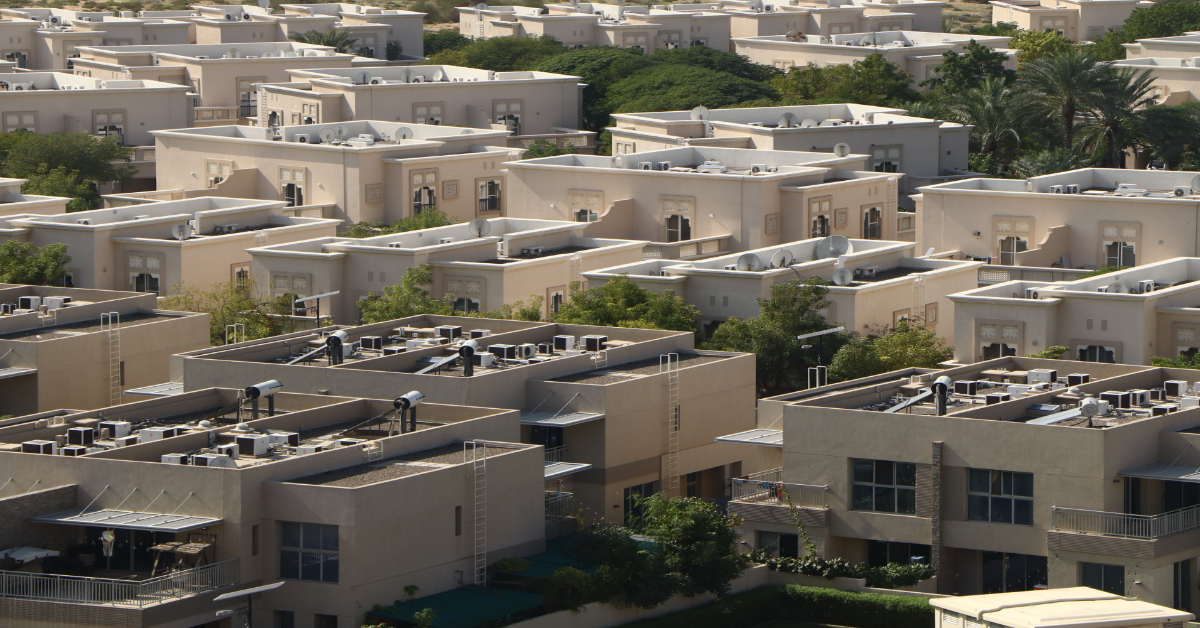 صورة جوية لمنطقة سكنية في دبي تُظهر هندسة معمارية حديثة وموحدة وسط المساحات الخضراء.