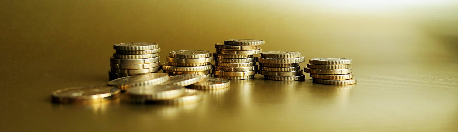Stacks of golden coins on a golden background.