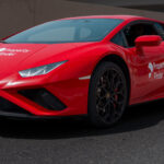 A red Lamborghini sports car branded with Property Finder and the slogan 'Drives my Success,' photographed on a Dubai street during the SuperAgent recognition event.