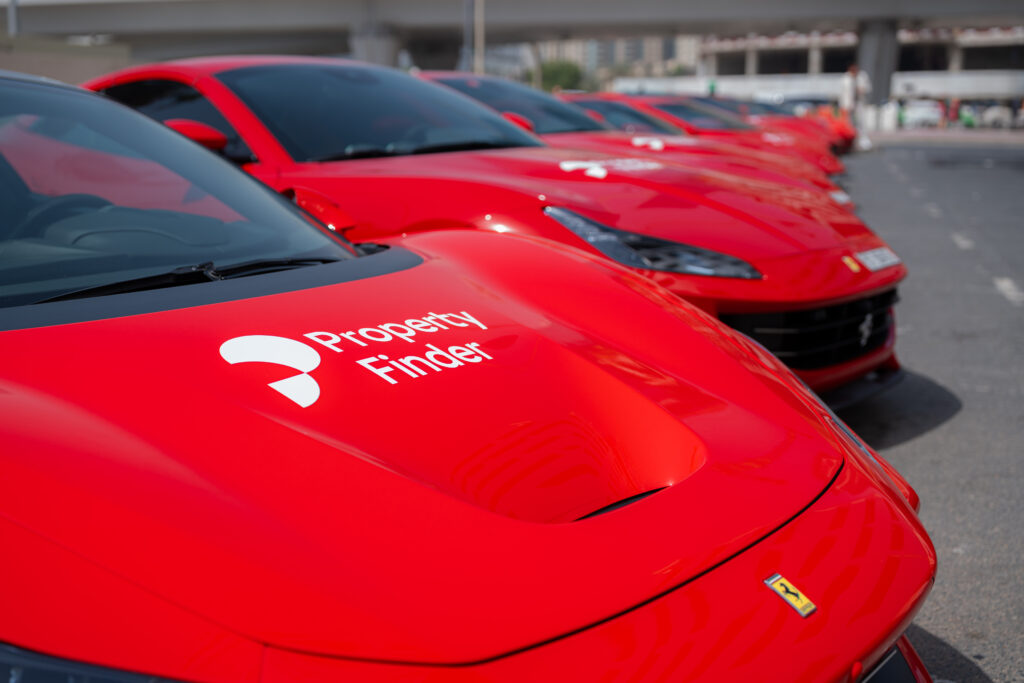 Close-up of red Ferrari sports cars branded with the Property Finder logo, lined up in Dubai for a SuperAgent recognition event.