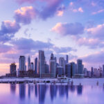 Panoramic view of Dubai Marina skyline at sunset, with vibrant clouds reflecting in calm waterfront, showcasing the city’s luxury real estate landscape.