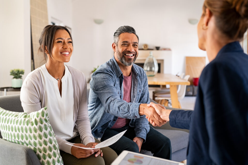 Real estate agent conducting a face-to-face meeting with smiling clients during a home consultation.
