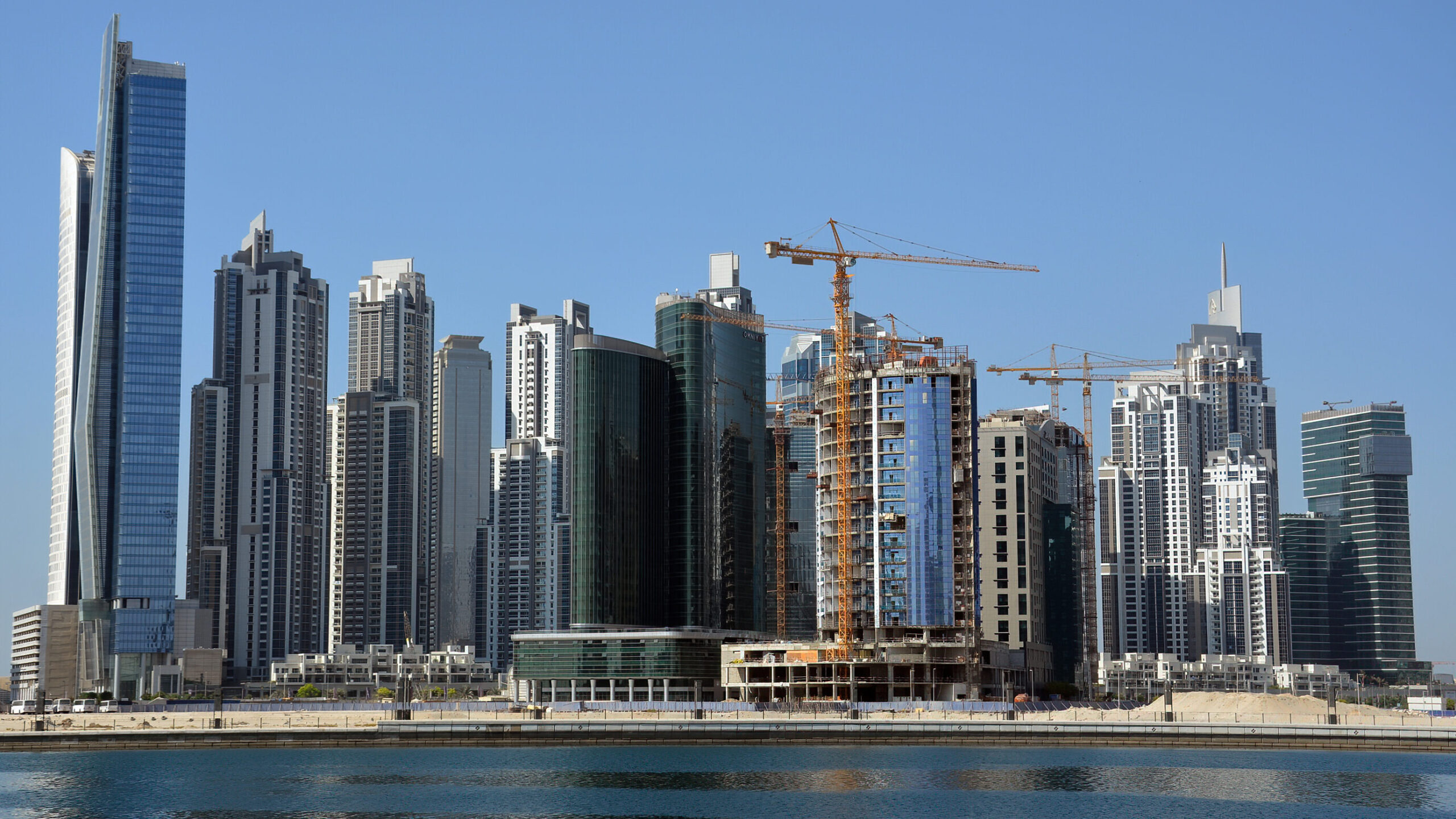 Dubai skyscrapers with cranes and new high-rise towers under construction, highlighting opportunities in off-plan real estate sales.