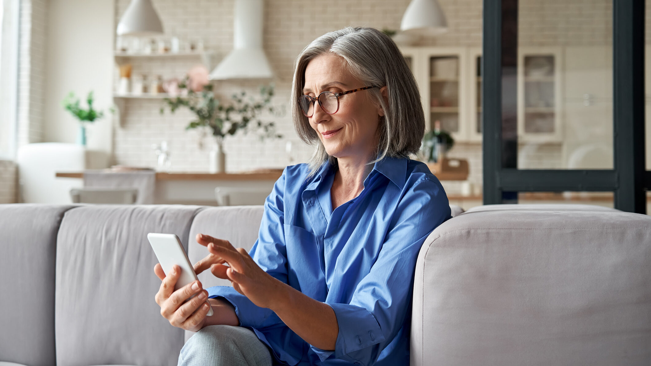 Smiling woman using a smartphone at home, representing a UAE real estate buyer engaging with WhatsApp opt-in funnels and property updates, highlighting user trust, clear consent, and mobile-first lead capture.