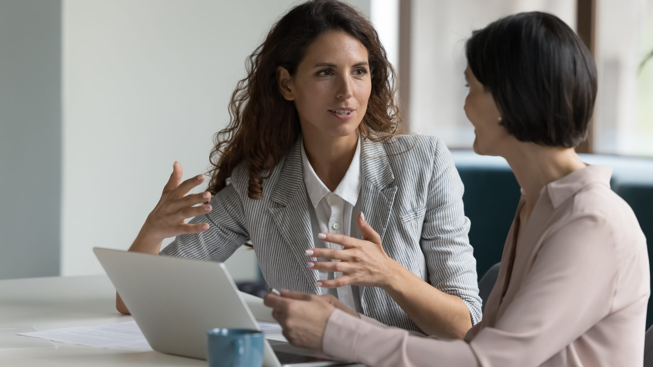 UAE real estate sales manager coaching an agent during a weekly quality assurance review, discussing call and WhatsApp transcripts, CRM notes, and objection-handling playbooks to improve conversion KPIs.