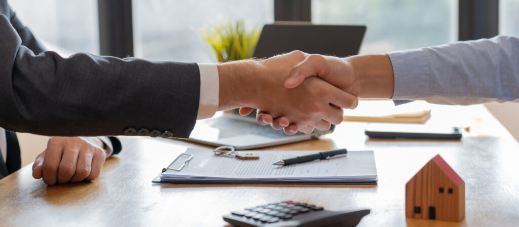 UAE real estate agent and client shaking hands over a signed property agreement, symbolising successful lead qualification, SLA-driven follow-up, and conversion from enquiry to closed deal.
