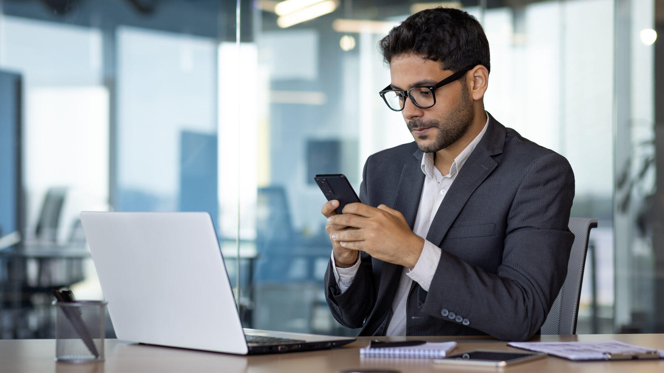 Real estate agent in a modern office using a smartphone to schedule WhatsApp broadcast messages, highlighting optimal timing, campaign planning, and structured communication for UAE property leads.