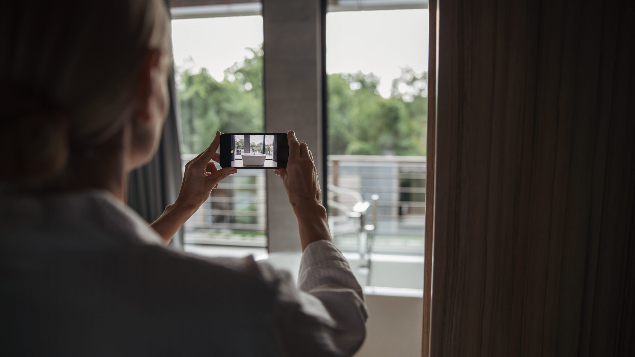 Real estate agent taking a smartphone photo of a balcony view for Dubai property listings and Instagram content.