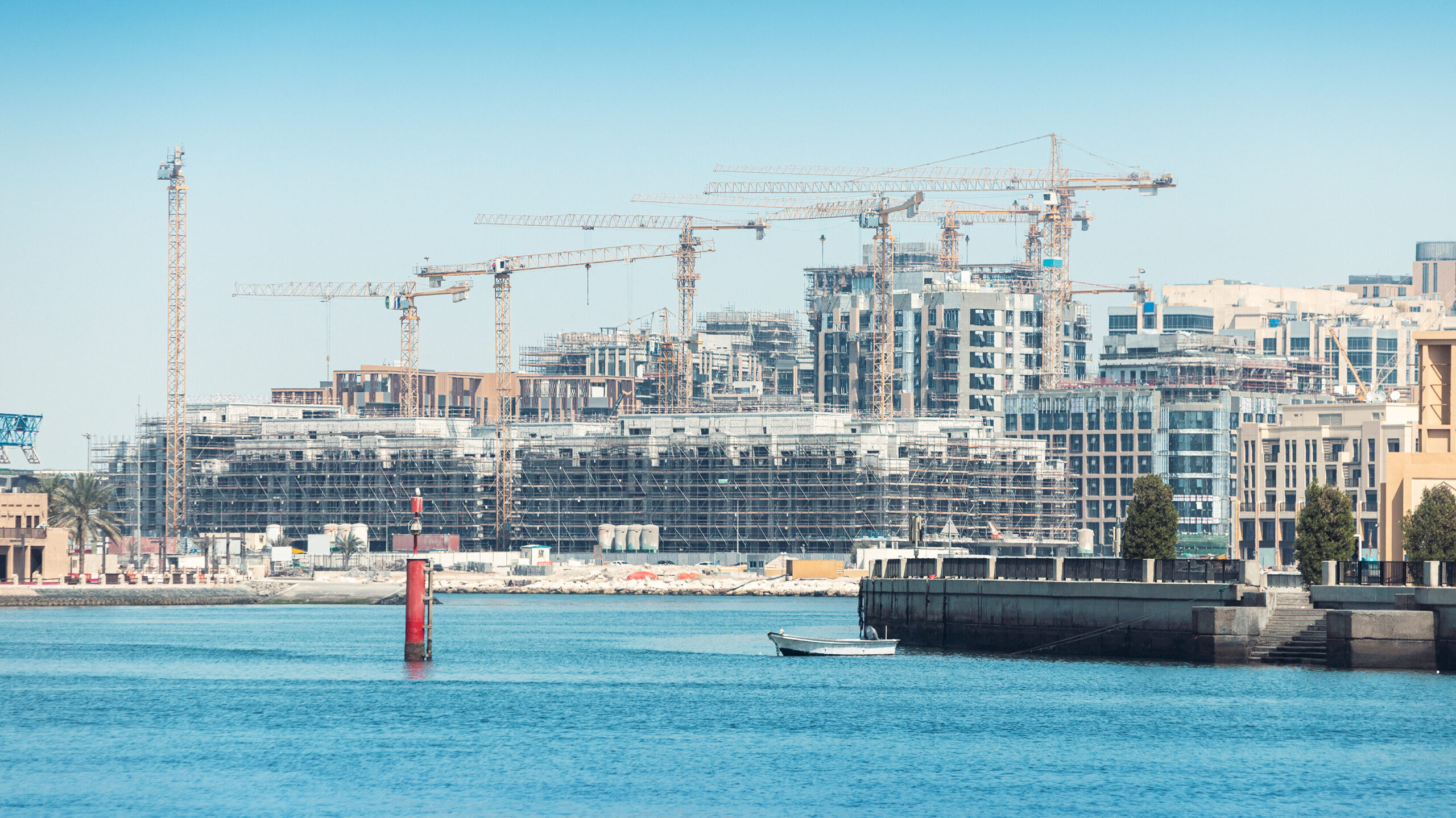 Waterfront residential towers under construction with cranes in Dubai, illustrating off-plan property development and new real estate supply in the city.