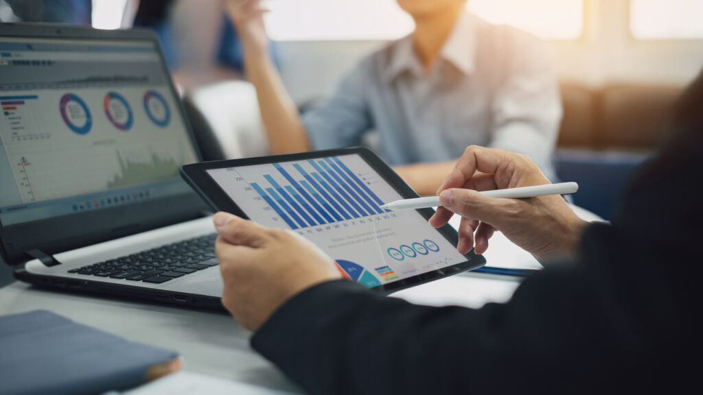 Investor reviewing real estate performance metrics on a tablet and laptop, analysing KPIs such as occupancy, lease-up velocity, and net effective rent for Dubai Build-to-Rent projects.