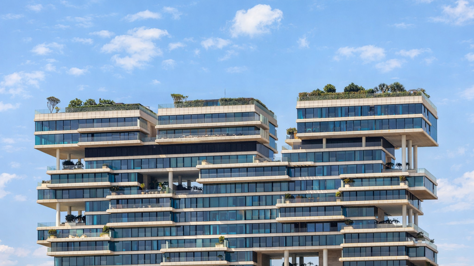 Modern luxury residential building with tiered architecture, rooftop gardens, and energy-efficient glass façades under a blue sky, showcasing sustainable real estate design in Dubai.
