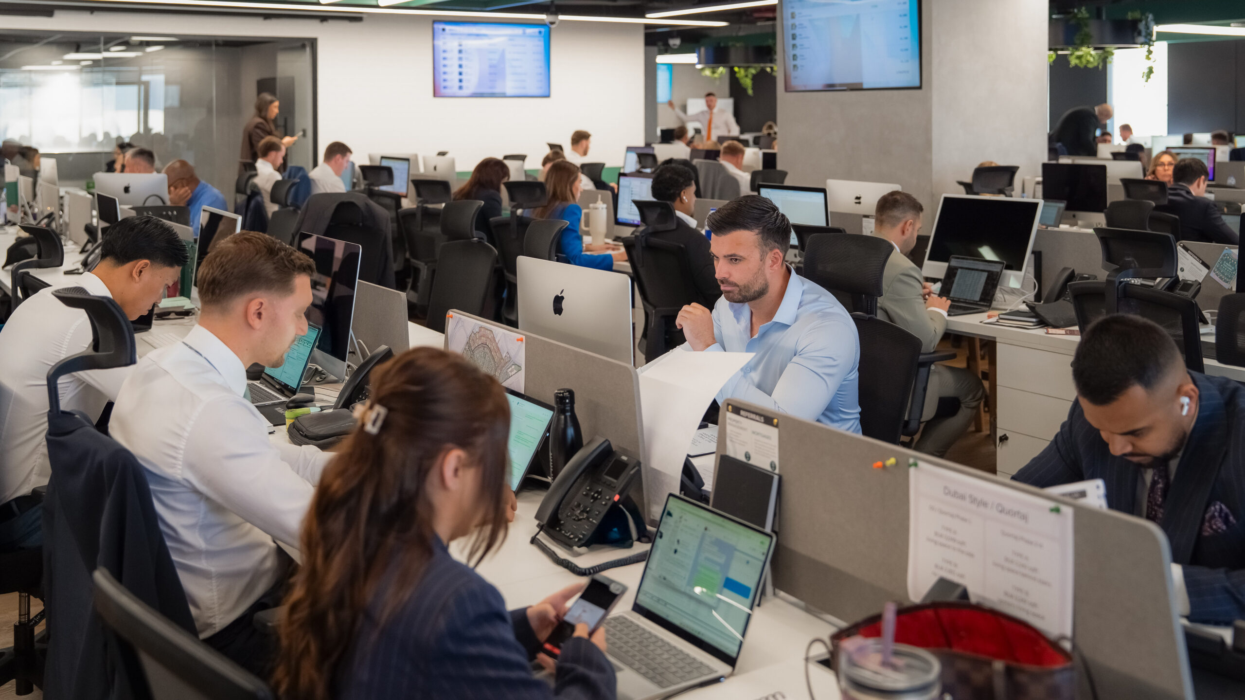 Hard-working real estate brokers working on the sales floor in a Dubai agency, illustrating how building the middle of the team strengthens performance and drives sustainable growth at the top.