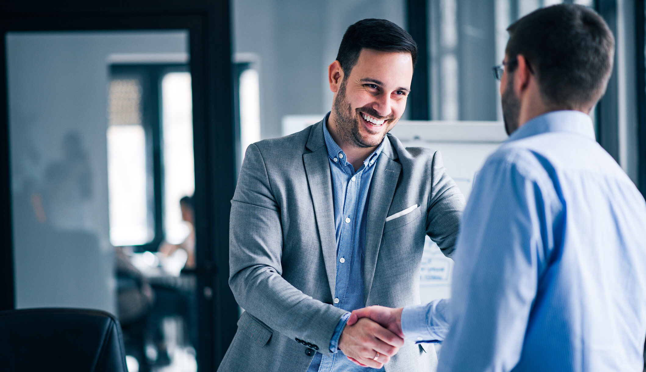 Dubai real estate agent shaking hands with a client during a property consultation in a modern office in the UAE