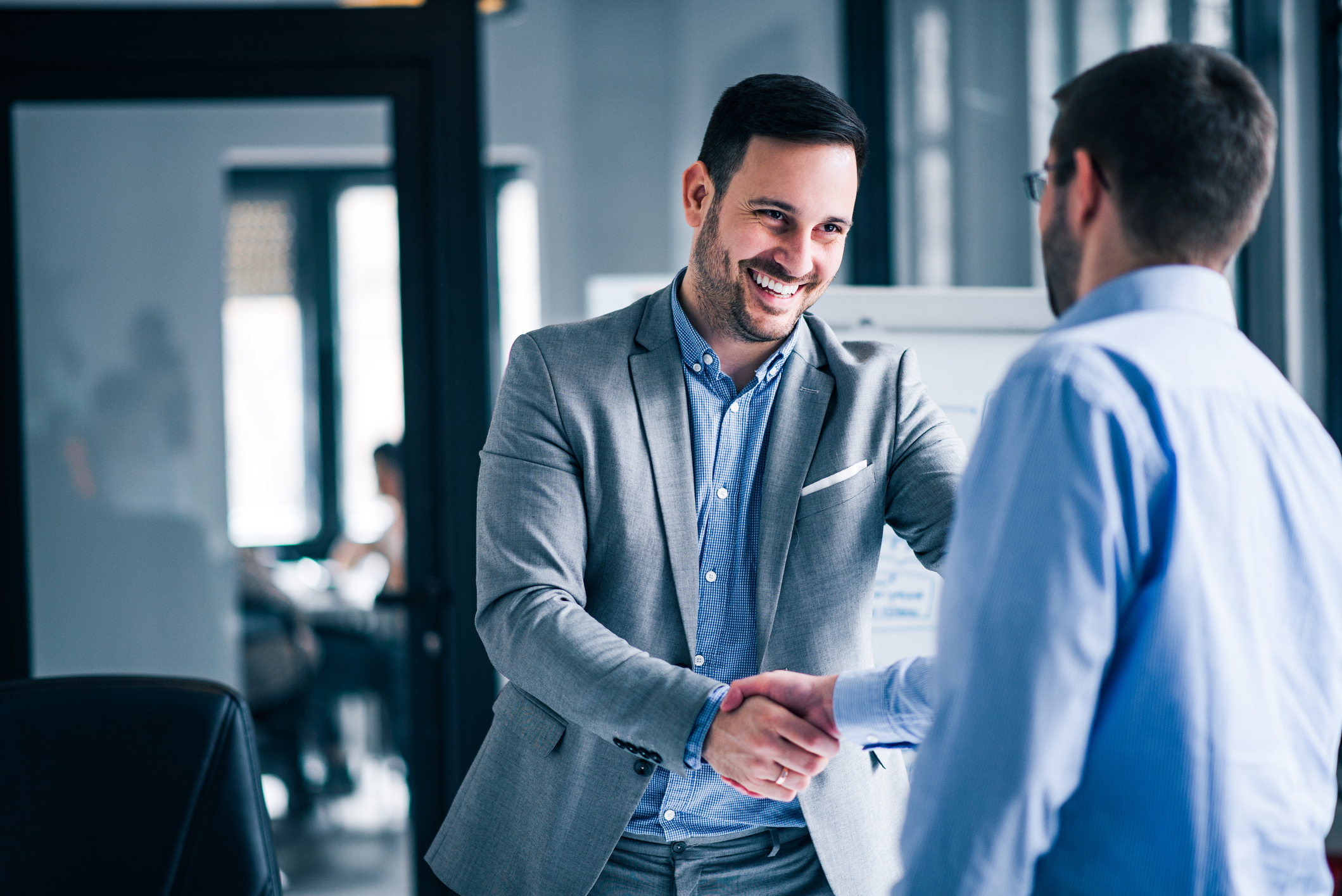 Dubai real estate agent shaking hands with a client during a property consultation in a modern office in the UAE